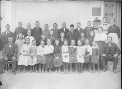 Gruppebilde 1900 -10  Ytre Enebakk skole
Gruppebilde med skoleelever, gutter og jenter, og med tre menn og tre kvinner. Bildet er tatt utenfor inngangen til poståpneriet, som lå i skolebygningen i Ytre Enebakk. Vår eller sommer.
Nøkkelord: gruppebilde;skoleelever;Ytre;gutter;jenter;poståpneri;skole;pyntet