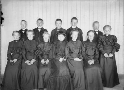 Gruppebilde 1900.  Ytre Enebakk
Konfirmasjonsbilde 7 jenter, 5 gutter. Svarte kjoler. Innendørs. 
Nøkkelord: gruppebilde;konfirmasjon;ytre;gutter;jenter;kjoler;smykker