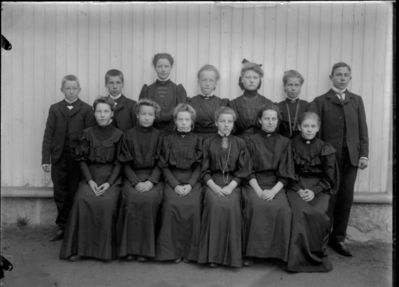 Gruppebilde 1908.  Ytre Enebakk
Konfirmasjonsbilde 10 jenter, 3 gutter. Utendørs, svarte kjoler. 
Nøkkelord: gruppebilde;konfirmasjon;ytre;gutter;jenter;agna;slette;rustad;kjoler,dress;smykker;utendørs