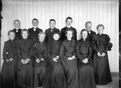Gruppebilde 1900 - 05  Ytre Enebakk
Konfirmasjonsbilde 7 jenter, 5 gutter. Svarte kjoler. Innendørs.
Nøkkelord: gruppebilde;konfirmasjon;ytre;gutter;jenter;kjoler;dress;pyntet;innendørs;smykker