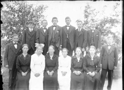 Gruppebilde 1905 -10  Ytre Enebakk
Konfirmasjonsbilde 6 jenter, 8 gutter. 2 i hvite kjoler, utendørs.
Nøkkelord: gruppebilde;konfirmasjon;ytre;gutter;jenter;kjoler;dress;pyntet;utendørs;smykker;tre;trær