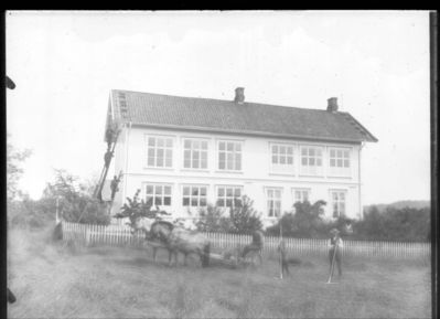 Bygning 1900 - 10  Ytre Enebakk skole
Ytre Enebakk skole fra hagesiden, tre malere i stige ved kortveggen, tre onnekarer med hesteforspann i ferd med å slå høy.
Nøkkelord: bygning;skole;ytre;hest;malere;stige;menn;hus;jorde;jordbruk;hage;hesteforspann;høy;gjerde