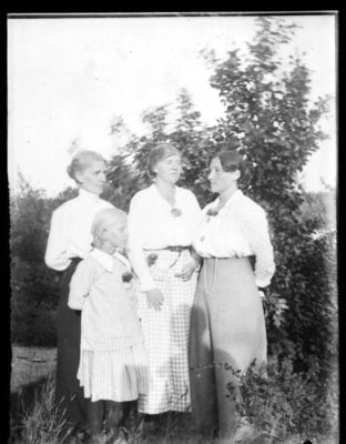 Gruppebilde  1910 - 15, Ytre Enebakk
Tre kvinner og liten pike stående utendørs. Sommer. Piken i front er Thrine Lorentsen f.1907. Bak fra venstre Anette Hansen, ukjent, Kamilla Tveit fra Sogn, lærer på Ytre, ble senere misjonær på Madegaskar. 
Nøkkelord: gruppe;barn;kvinner;ytre;1910