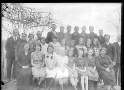 Gruppebilde  1920 - 30
Voksne og ungdommer/barn. Utendørs sommer. Nr. to fra høyre bak Helge Waldemar Skaug
Nøkkelord: gruppe;barn;gutter;jenter;helge;waldemar;skaug;ungdom