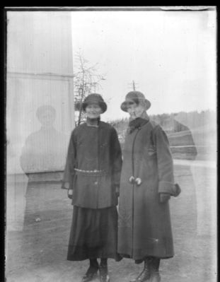 Portrett ca. 1920
To kvinner i yttertøy utendørs. Bildet dobbelteksponert.
Nøkkelord: portrett;kvinner;damer